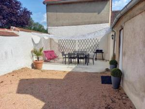 un patio con tavolo e sedie in un edificio di Maison cocooning avec jardin et cheminée près de Vichy – vélos et animaux acceptés - FR-1-489-68 a Broût-Vernet