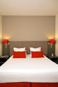 a large bed with two red pillows on it at Residhome Reims Centre in Reims