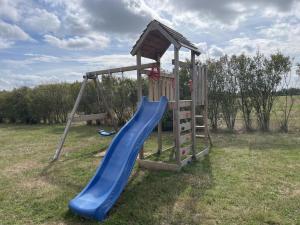 un parco giochi con scivolo blu in un campo di Charmants chalets au bord du lac avec terrasse, activités nautiques et pêche, animaux acceptés, tout inclus - FR-1-489-361 a Pierrefitte-sur-Loire