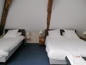 two beds in a room with white sheets and pillows at Gîte historique rénové avec jardin et WiFi - FR-1-489-571 in Theneuille