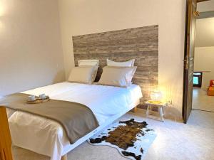 a bedroom with a large white bed with a wooden headboard at Gîte cosy avec spa, grand jardin, proche de la rivière Sioule - idéal pour famille et relaxation - FR-1-489-342 in Saint-Bonnet-de-Rochefort