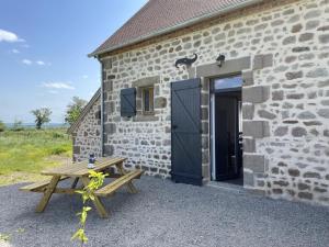 drewniany stół piknikowy obok kamiennego budynku z drzwiami w obiekcie Charmant gîte à la ferme avec tout confort, proche de Bourbon-l'Archambault, idéal pour randos et curistes - FR-1-489-432 w mieście Ygrande