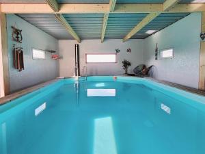 a swimming pool with blue water in a room at Refuge familial avec piscine, aire de jeux et confort moderne à Blomard - FR-1-489-465 in Blomard