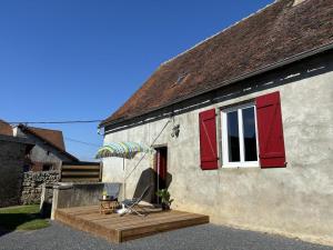 une maison avec des fenêtres à volets rouges, une chaise et un parapluie dans l'établissement Maison vignoble avec terrasse et BBQ à Saulcet, animaux admis - FR-1-489-544, à Saulcet