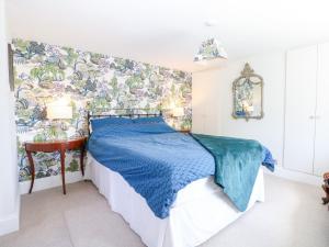 een slaapkamer met een blauw bed en een muurschildering bij Cherry Garden Cottage in Cranbrook