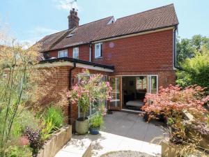 een bakstenen huis met een patio ervoor bij Cherry Garden Cottage in Cranbrook