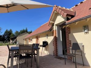 a patio with a table and chairs and an umbrella at Gîte de charme à Thiel-sur-Acolin : terrasse, grand terrain, barbecue et équipements modernes - FR-1-489-338 in Thiel-sur-Acolin