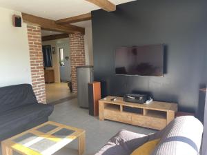 a living room with a couch and a tv on the wall at Gîte nature à St Léon avec jardin et WIFI - FR-1-489-440 in Saint-Léon