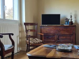 a living room with a table and a television on a dresser at Gîte cosy avec terrasse et WiFi - 2 ch, 4 pers à Besson - FR-1-489-355 in Besson
