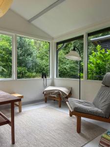a room with windows and a chair and a table at Nature-Rich 60S Holiday Home By Isefjord in Jægerspris +22 photos