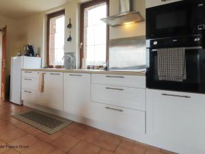 a kitchen with white cabinets and a black microwave at Gîte paisible en Normandie avec WiFi, animaux admis - FR-1-497-227 in La Trinité-des-Laitiers +12 photos