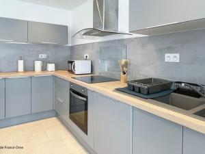 a kitchen with blue cabinets and a sink and a microwave at Maison rénovée avec WIFI et animaux admis, près de la Suisse Normande - FR-1-497-242 in Saint-Pierre-du-Regard +2 photos
