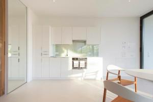 a kitchen with white cabinets and a table and chair at Designer South Side Apartment In The Dolomites in Bolzano