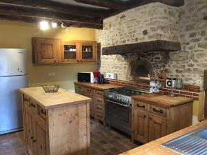 a kitchen with a stove and a stone wall at Grande maison familiale avec jardin clos, ping-pong et proche châteaux UNESCO - FR-1-491-402 in Prénouvellon
