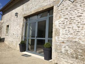 a glass door on a brick building with two potted plants at Grande maison familiale avec jardin clos, ping-pong et proche châteaux UNESCO - FR-1-491-402 in Prénouvellon