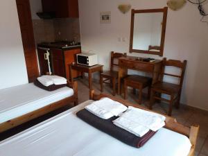 a bedroom with two beds and a desk and a mirror at Hotel Kosmas in Sarti