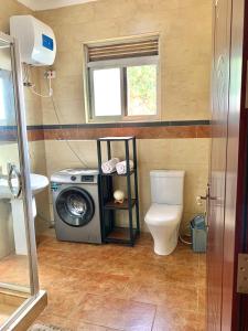 a bathroom with a washing machine and a toilet at WanderHome - 1RM in Kampala