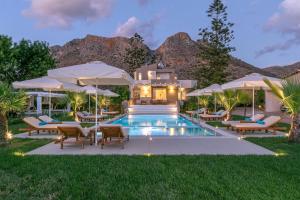 a pool with chairs and umbrellas in front of a house at Azure Cove Villa Kalathas Bay Luxury Redefined Serenity And Privacy Unforgettable Cretan Escape in Stavros