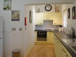 a kitchen with yellow cabinets and a clock on the wall at High Moor Cottage in Dufton