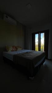 een bed in een donkere kamer met een raam bij Chalés Dunas - Icaraí de Amontada in Amontada
