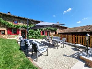 a patio with tables and chairs and an umbrella at Gîte spacieux 10 pers: Nature, Spa, Confort - FR-1-496-358 in Saint-Denis-sur-Coise