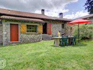 a table and chairs with an umbrella in front of a house at Chalet familial à 5 min des pistes de ski de Chalmazel, 3 chambres, cheminée, animaux acceptés - FR-1-496-138 in Le Champas
