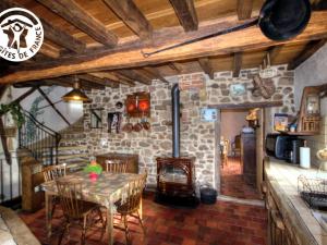 una sala da pranzo con tavolo e camino in pietra di Gîte charmant avec four à pain, jardin, terrasse, jeux et poêle à bois, acceptant animaux - FR-1-496-137 a Chirassimont