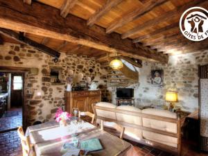 un soggiorno con pareti in pietra e soffitto in legno di Gîte charmant avec four à pain, jardin, terrasse, jeux et poêle à bois, acceptant animaux - FR-1-496-137 a Chirassimont