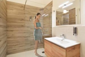 a woman standing in a shower in a bathroom at FIORELLI rooms in Bosa