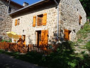 una vecchia casa in pietra con finestre in legno e recinzione di Charmant Gîte avec Terrasse, Cheminée et Jardin, à Proximité des Bois, Animaux Acceptés - FR-1-496-205 a Saint-Jean-Soleymieux