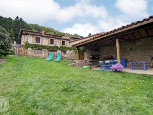 una casa con cortile con sedie e tavolo di Gîte rénové avec cheminée et jardin à 15 km des pistes de ski - FR-1-496-9 a Saint-Bonnet-le-Courreau