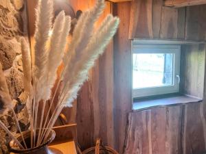 Un jarrón con plumas en una habitación con ventana. en Gîte familial dans le massif du Pilat avec confort inclus - FR-1-496-294, en Doizieux