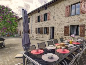 un patio con tavoli, sedie e un ombrellone di Gîte en pierre rénové avec jardin et WiFi à Chalmazel-Jeansagnière - FR-1-496-253 a Chalmazel Jeansagniere