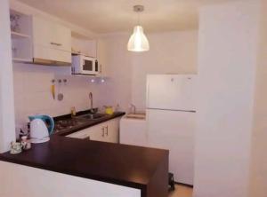 a kitchen with a white refrigerator and a sink at Lomas de Papudo in Papudo