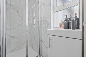 a bathroom with a shower with a sink and a mirror at Central Luxe Flats With Spa Facilities in Cardiff +18 photos