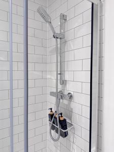 a shower with two bottles in a white tile bathroom at Eden Gateway full equipment brand new bright and modern En-suite Double bedroom - room 3 near city centre in Birmingham +12 photos