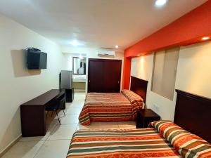 a hotel room with two beds and a television at Hotel Villa de Altamira in Altamira