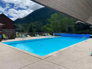Una gran piscina azul con montañas al fondo. en T2 tout confort Ax les thermes, en Ax-les-Thermes