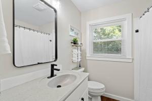 Un baño blanco con lavabo y espejo. en Cottage Under the Magnolia Trees, en Beaufort