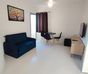 Una sala de estar con un sofá azul y una mesa. en Apartamento Excelente Liberdade SP, en São Paulo