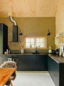 a kitchen with black cabinets and a wooden ceiling at Designed House With Recycled Details In Österlen in Köpingebro