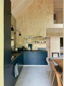 a large kitchen with blue cabinets and a table at Designed House With Recycled Details In Österlen in Köpingebro