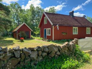 ein rotes Haus mit einer Steinmauer davor in der Unterkunft Family-Friendly Cottage Near The Sea In Ugglarp in Heberg + 9 Fotos
