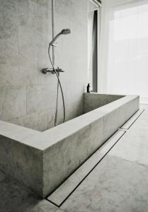 a bath tub with a shower in a bathroom at Architect-Designed House With Sea View In Ljugarn in Ljugarn