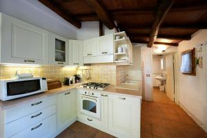 a kitchen with white cabinets and a stove top oven at Historic Villa Overlooking Lake Trasimeno in Paciano