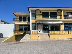 a yellow building with a parking lot in front of it at Quartos, Solar da São in Nazaré