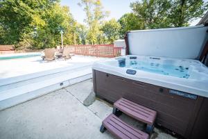 a bath tub with a chair next to a pool at Lush Hideaway with HotTub & Pool 6 mins kings Island in Mason
