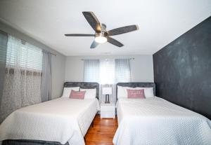 two beds in a room with a ceiling fan at Lush Hideaway with HotTub & Pool 6 mins kings Island in Mason