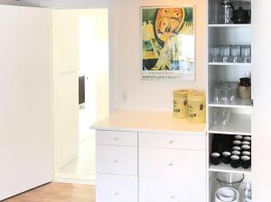 a kitchen with white cabinets and a painting on the wall at Renovated Farmhouse By The Beach On Møn in Stege