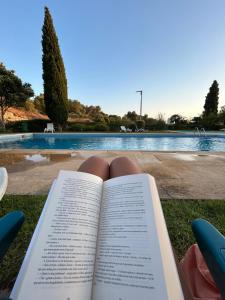 un livre posé sur l'herbe à côté d'une piscine dans l'établissement Alvor Prime BeachStudio, à Alvor